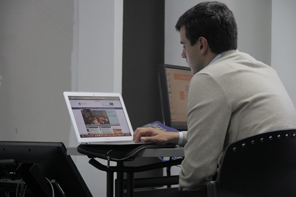 Hombre joven sentado y mirando la pantalla de un computador portátil