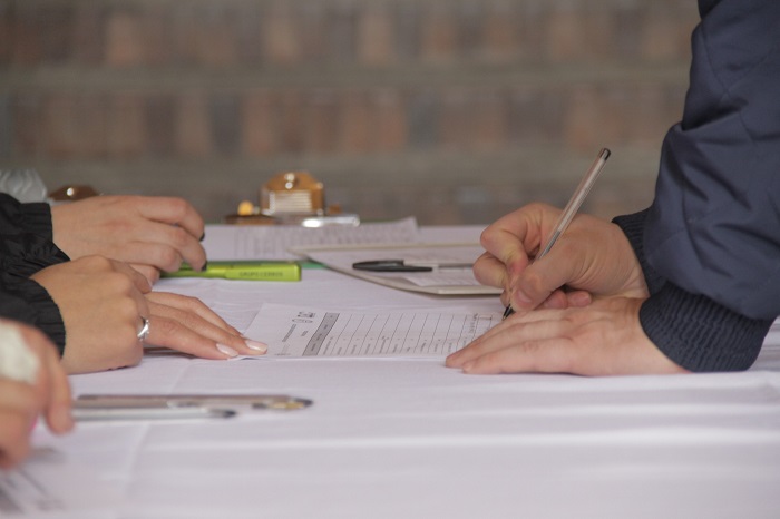Manos de hombre diligenciando un formulario sobre una mesa