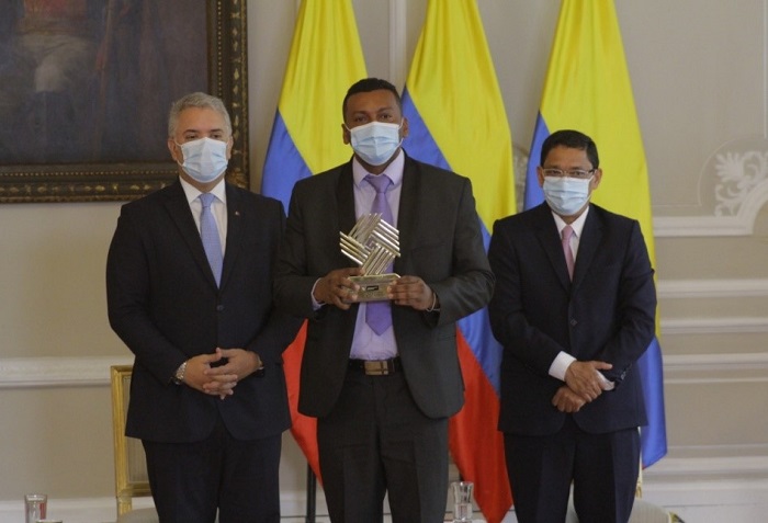 De pie frente a la bandera de Colombia se observa al presidente Iván Duque, un ganador del Premio Nacional de Alta Gerencia y el director de Función Pública, Nerio José Alvis Barranco