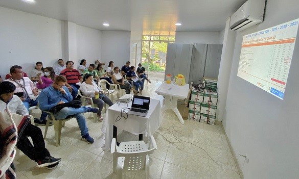 Grupo de personas sentadas prestando atención a una presentación que se está proyectando en la pared