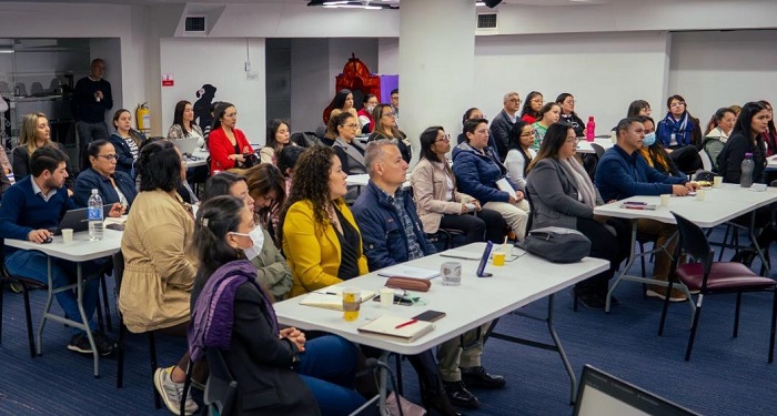 Grupo grande de servidores públicos, hombre y mujeres, sentados en un auditorio